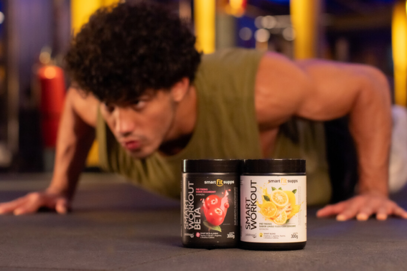 A imagem apresenta um homem fazendo flexão e, a frente, estão dois Smart Fit Supps.